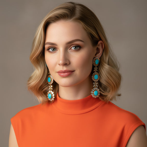 Woman wearing turquoise and diamond slice earrings with an orange top against a neutral background