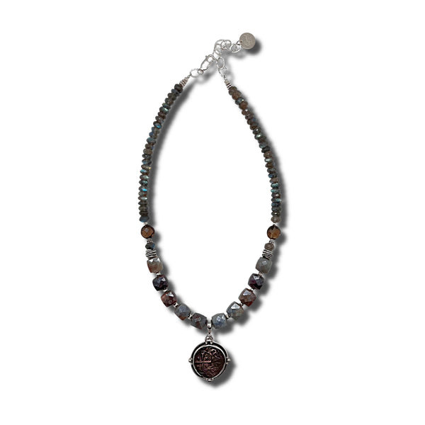 Necklace with beaded chain and an ancient coin pendant on a white background