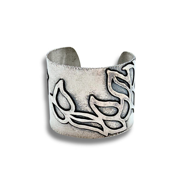 A wide silver cuff bracelet with an oxidized leaf pattern, photographed on a clean white background.