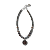 Necklace with beaded chain and an ancient coin pendant on a white background