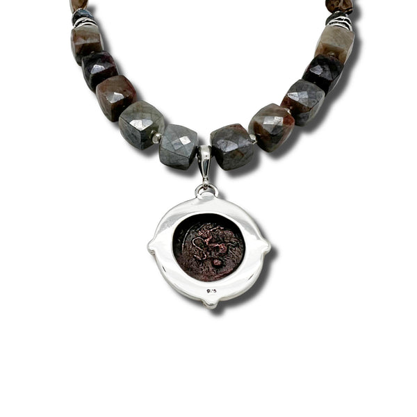 Necklace with beaded chain and an ancient coin pendant on a white background