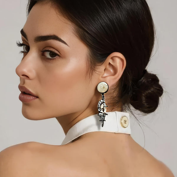 A close-up of a woman wearing a dangling statement earring. The earring features a round cream-colored fossil coral top with a cream and grey fossil wood drop set in oxidized silver.