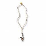 A delicate gold and black chain necklace with a unique wavy pendant featuring a small gold moonstone and black metal details, displayed on a clean white background.