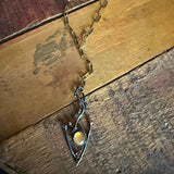 A handmade pendant necklace featuring a gold moonstone cabochon stone surrounded by a silver bezel, set on a rustic wooden background.